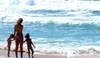 Žena s dětmi jdoucí po pláži kolem moře
