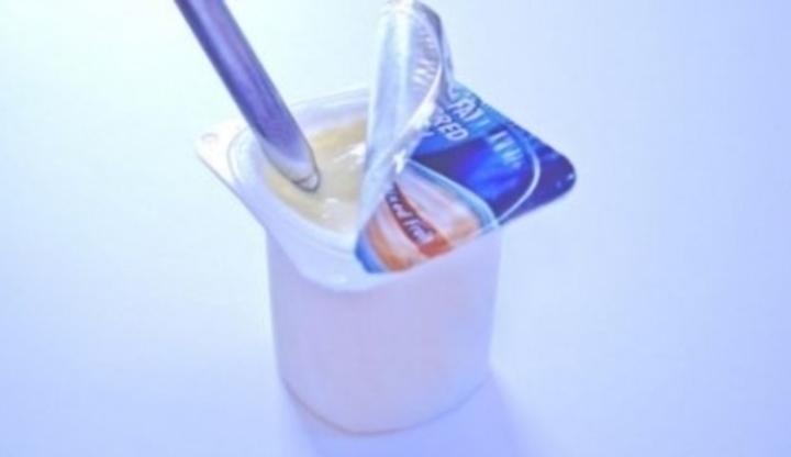 Otevřený kelímek jogurtu s ponořenou lžičkou