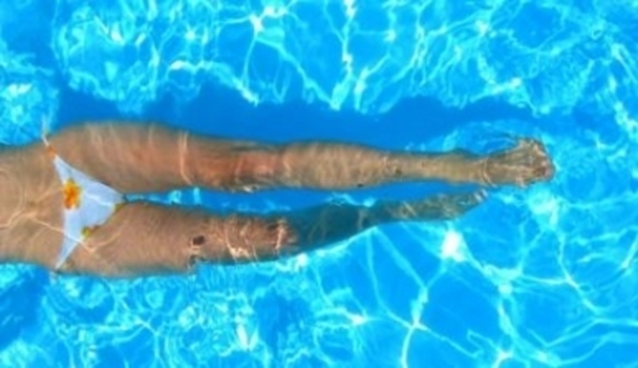 Ženské nohy pod vodou v bazénu 