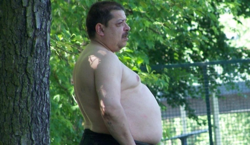 Obézní muž stojící u stolu 