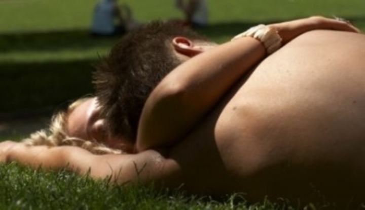 Dvojice v objetí ležící na trávě 