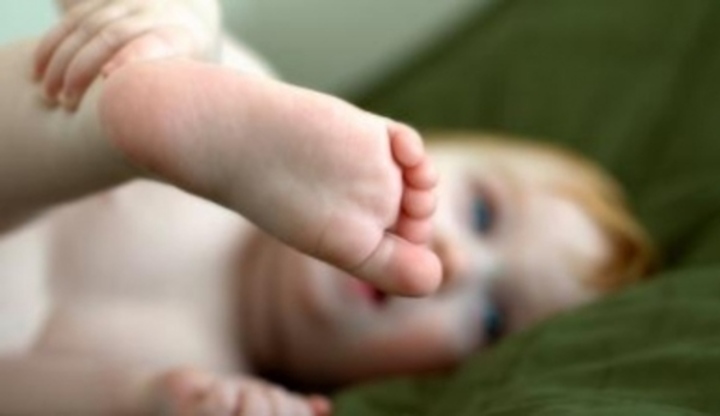 Ležící miminko držící si nohu 