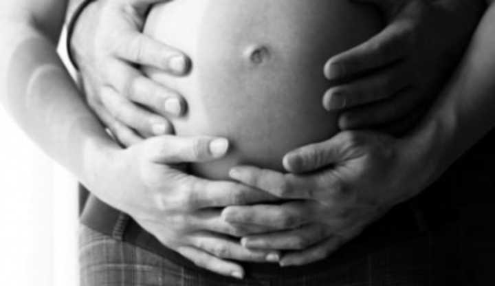 Ruce držící těhotenské bříško 