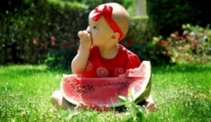 Dítě s kusem melounu sedící na trávě 
