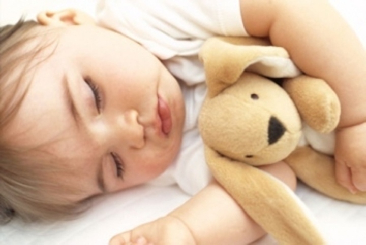 Spící dítě držící plyšového pejska 