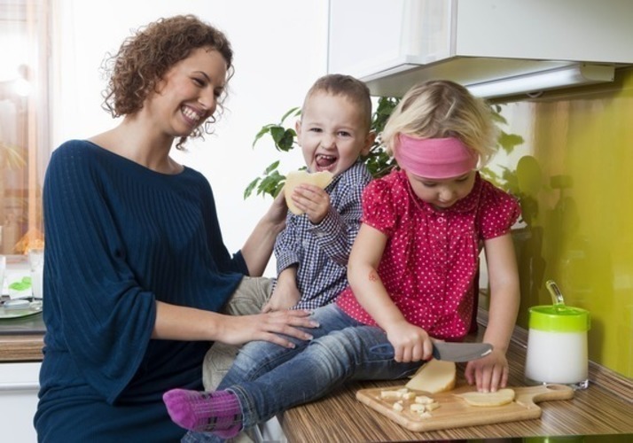 Žena drží děti sedící na kuchyňské lince 