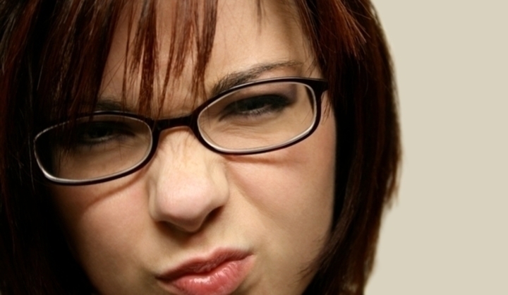 Žena s dioptrickými brýlemi a přivřenýma očima